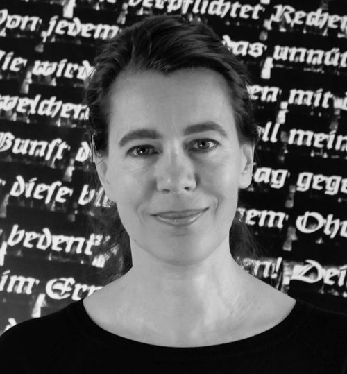 Porträt von Nicole Brey vor einer Wand mit Frakturschrift-Zitaten